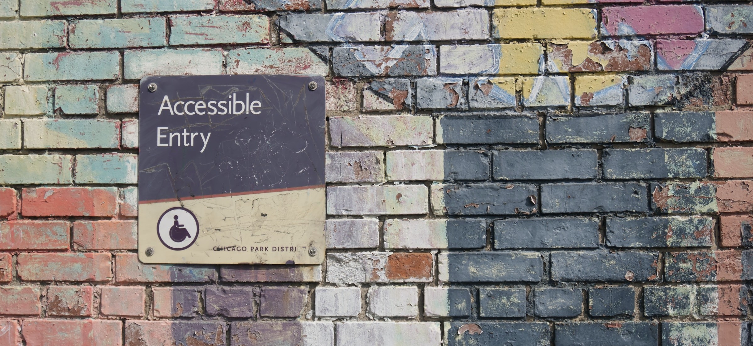 An "Accessibile Entry" sign on a multi-colored brick wall